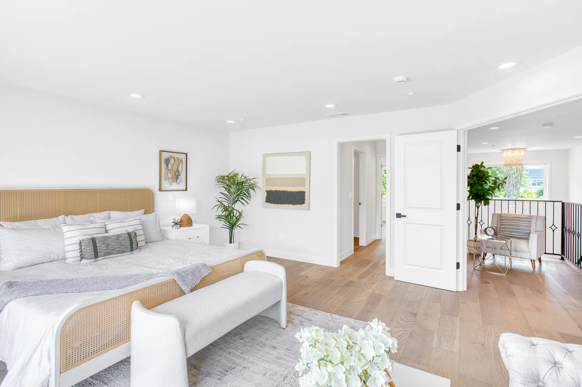 Bright remodeled bedroom with light wood flooring, white walls, and a wide doorway