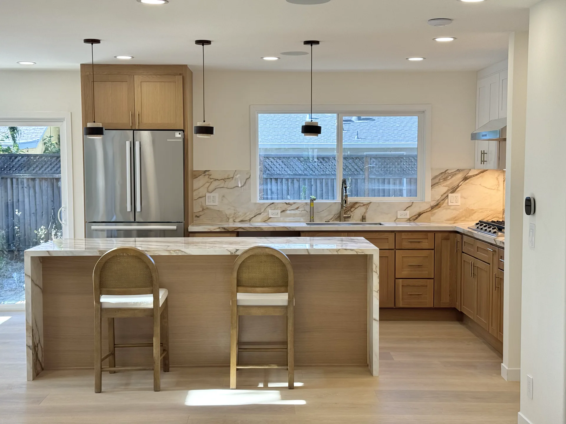 Compact kitchen with warm wood cabinets, a peninsula, and marble-pattern backsplash