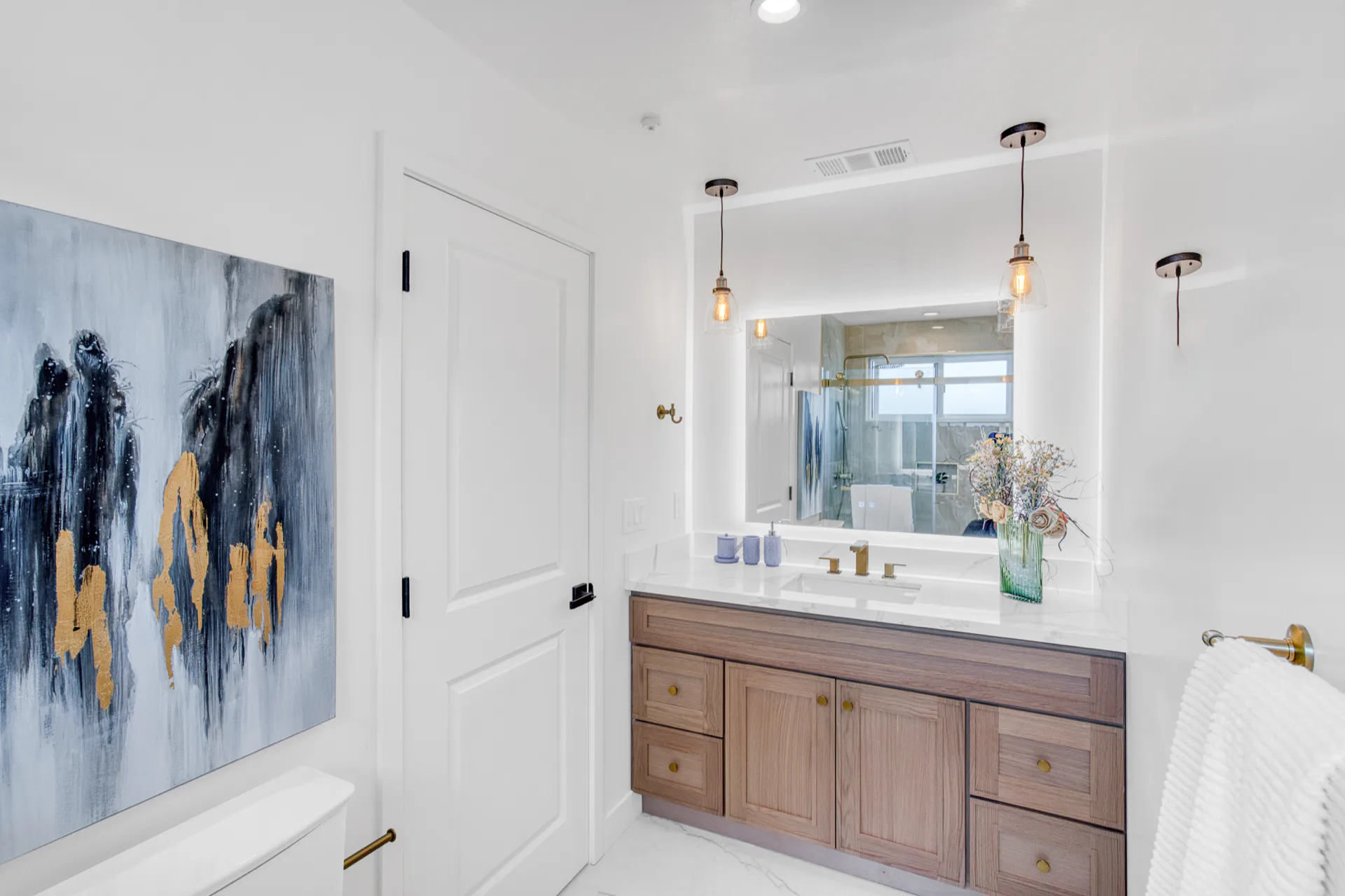 Bathroom remodel with a floating wood vanity, round mirror, and abstract wall art