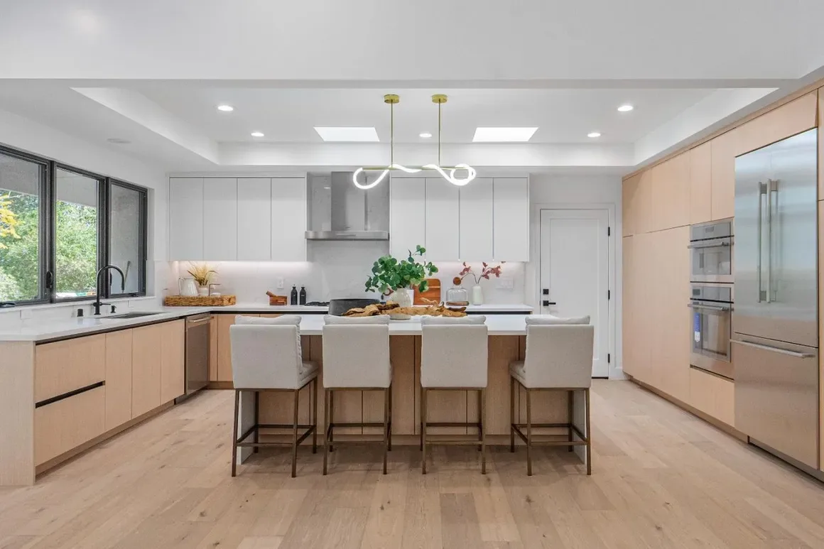 Open-plan oak kitchen with a large island, skylights, and an adjacent dining room
