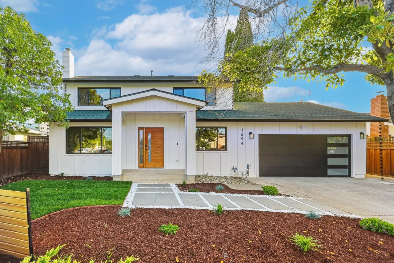 Updated two-story home exterior with white siding, a wood entry door, and a black garage door
