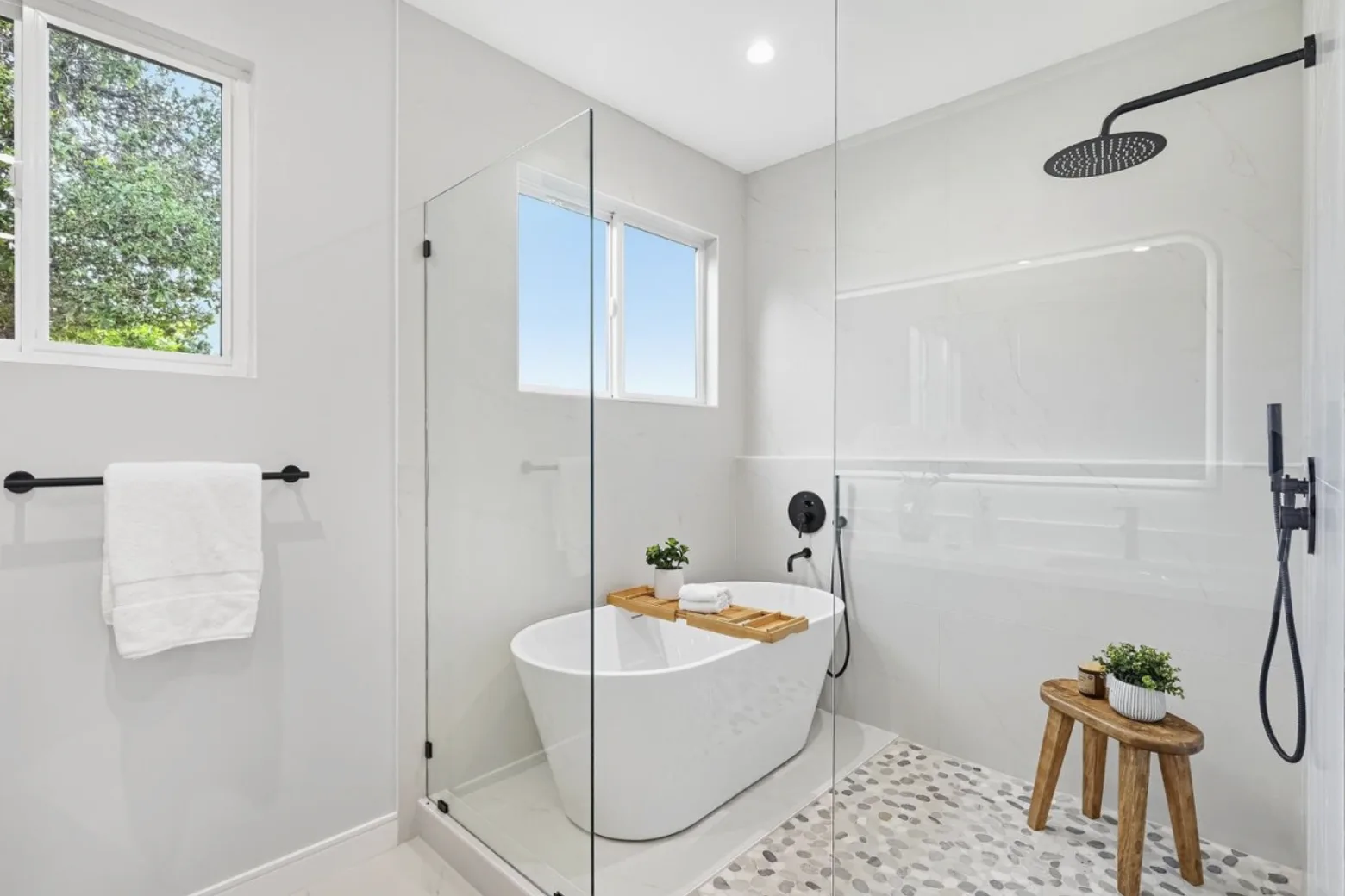 Bathroom remodel with a glass walk-in shower, freestanding tub, and black fixtures