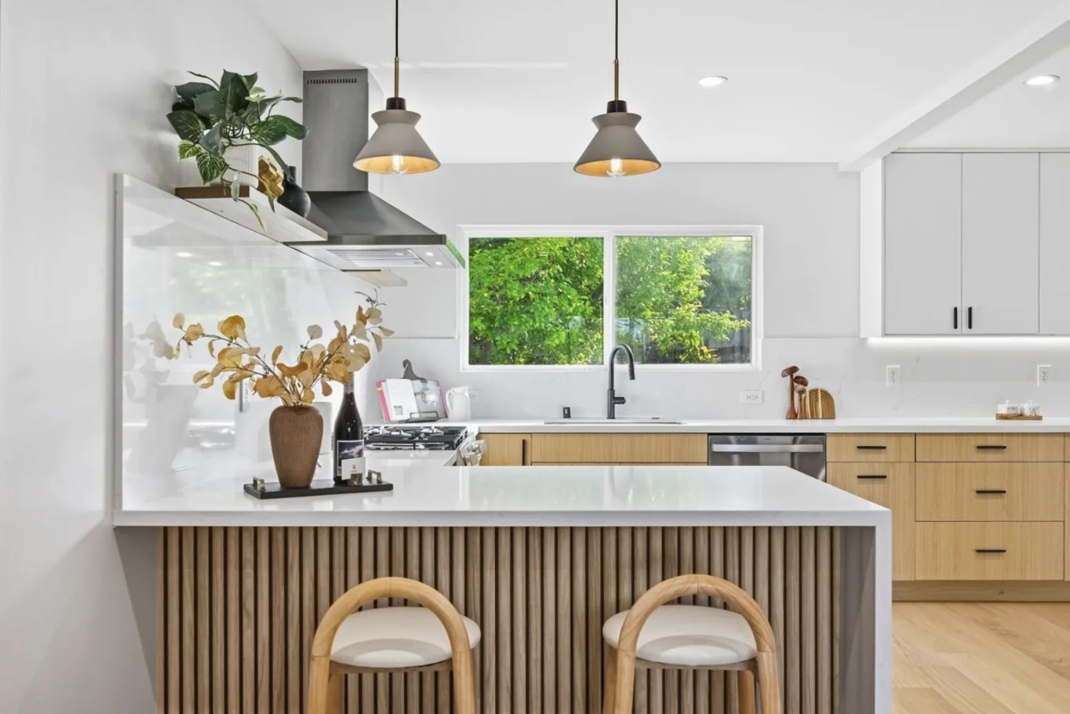 White oak kitchen island with counter seating, globe pendants, and white cabinetry